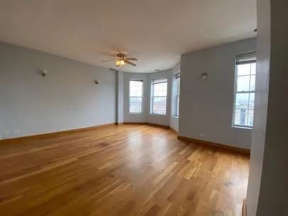 a view of an empty room with window and wooden floor