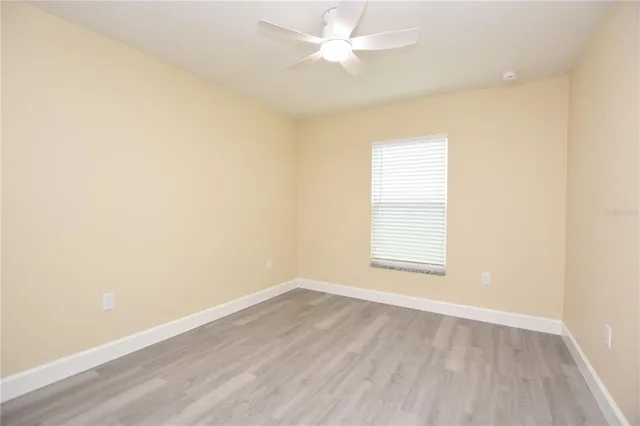 an empty room with wooden floor and fan