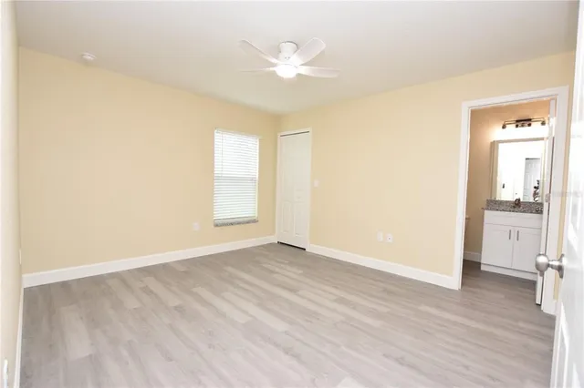 an empty room with wooden floor and fan
