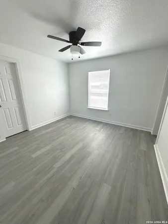 an empty room with wooden floor fan and windows