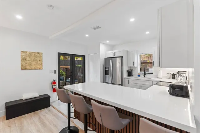 a kitchen with stainless steel appliances a dining table chairs and refrigerator