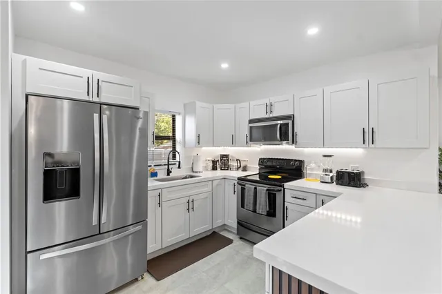 a kitchen with stainless steel appliances a refrigerator sink and stove top oven