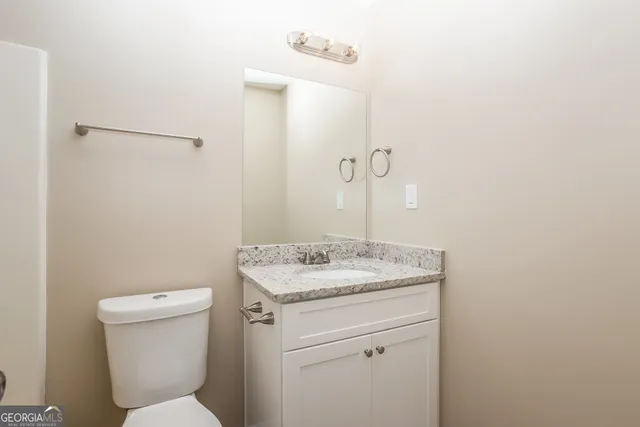 a bathroom with a granite countertop toilet and a sink