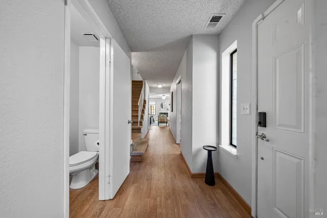 a view of a hallway with wooden floor and a bathroom