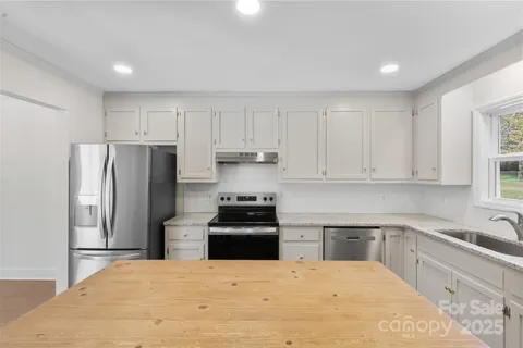 a kitchen with granite countertop white cabinets and stainless steel appliances