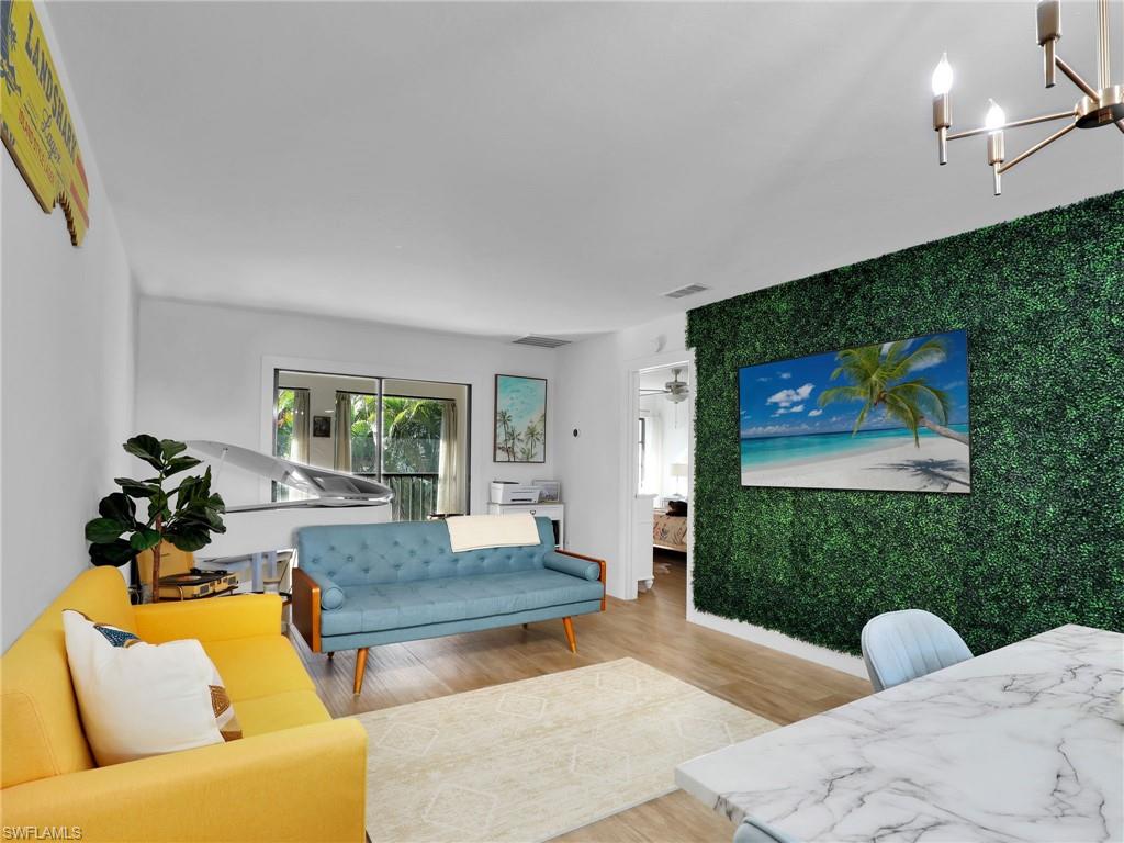 9831 Alabama Street, Unit 5 Bonita Springs, FL 34135 - Photo 12 of 28 Living area with an accent wall, light wood finished floors, and a chandelier