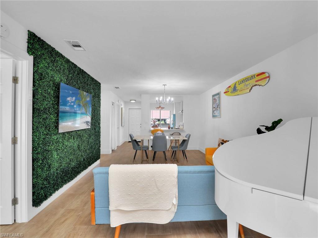 9831 Alabama Street, Unit 5 Bonita Springs, FL 34135 - Photo 15 of 28 Living area featuring a chandelier, an accent wall, and wood finished floors