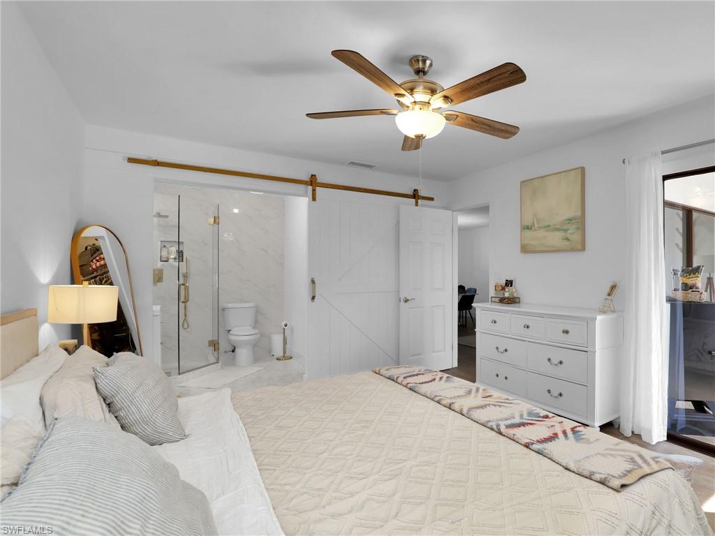 9831 Alabama Street, Unit 5 Bonita Springs, FL 34135 - Photo 18 of 28 Bedroom with a barn door, connected bathroom, and ceiling fan