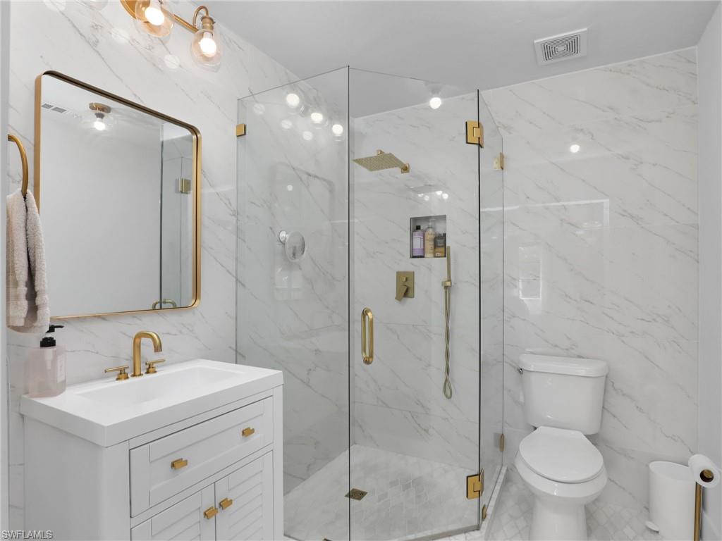 9831 Alabama Street, Unit 5 Bonita Springs, FL 34135 - Photo 19 of 28 Bathroom with vanity, tile walls, a marble finish shower, and stone wall