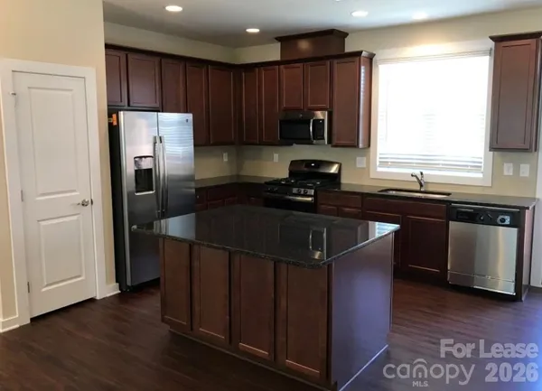 a kitchen with kitchen island granite countertop a sink appliances cabinets and counter space