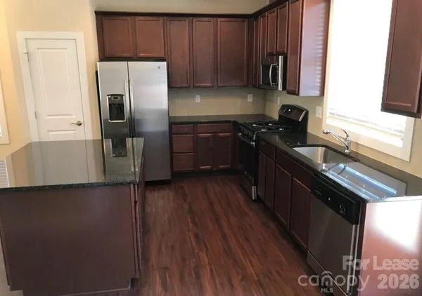 a kitchen with a sink a refrigerator and wooden cabinets