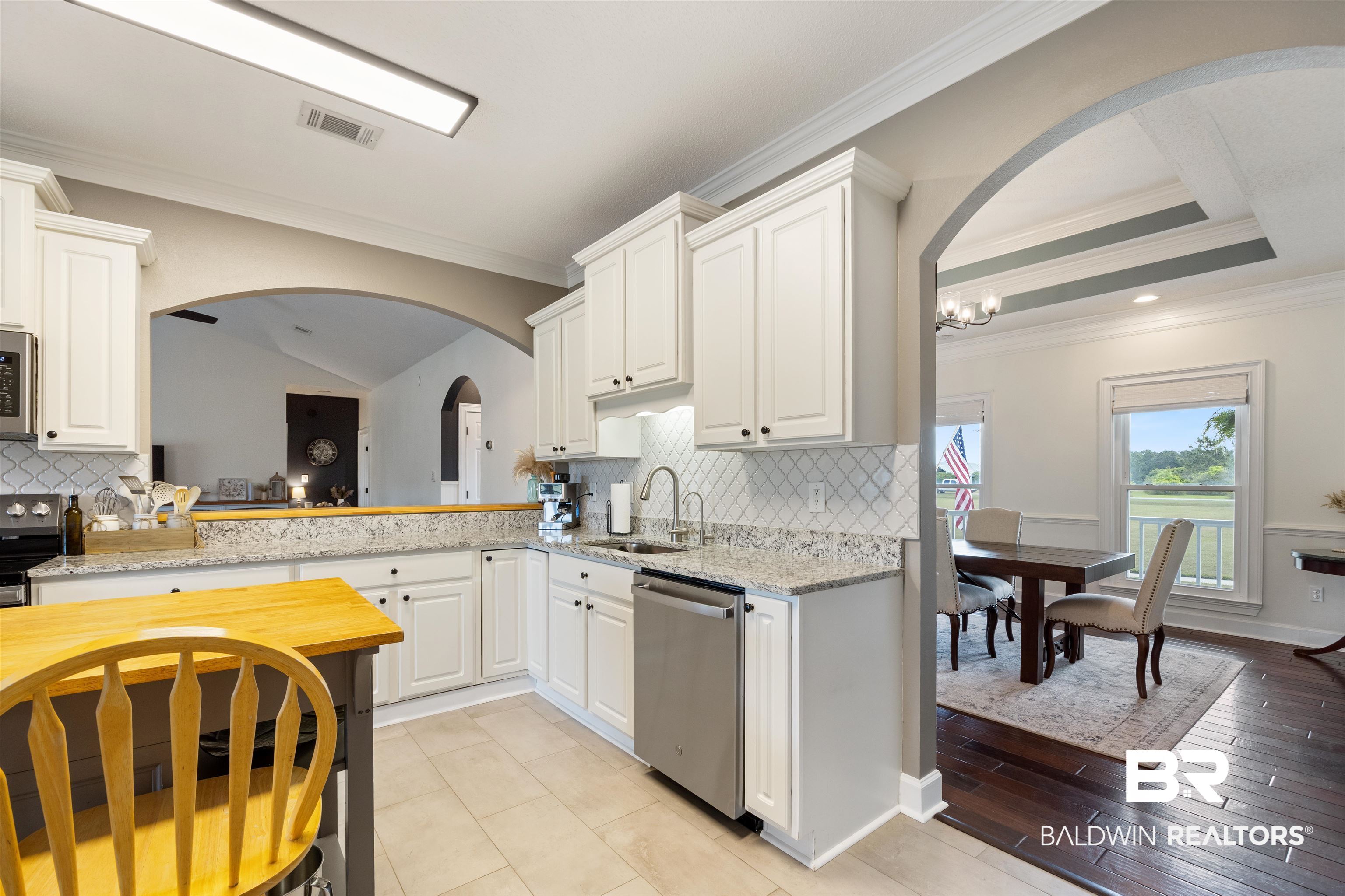 9855 Stucki Road Elberta, AL 36530 - Photo 24 of 54 Kitchen with arched walkways, backsplash, light stone countertops, ornamental molding, and stainless steel appliances