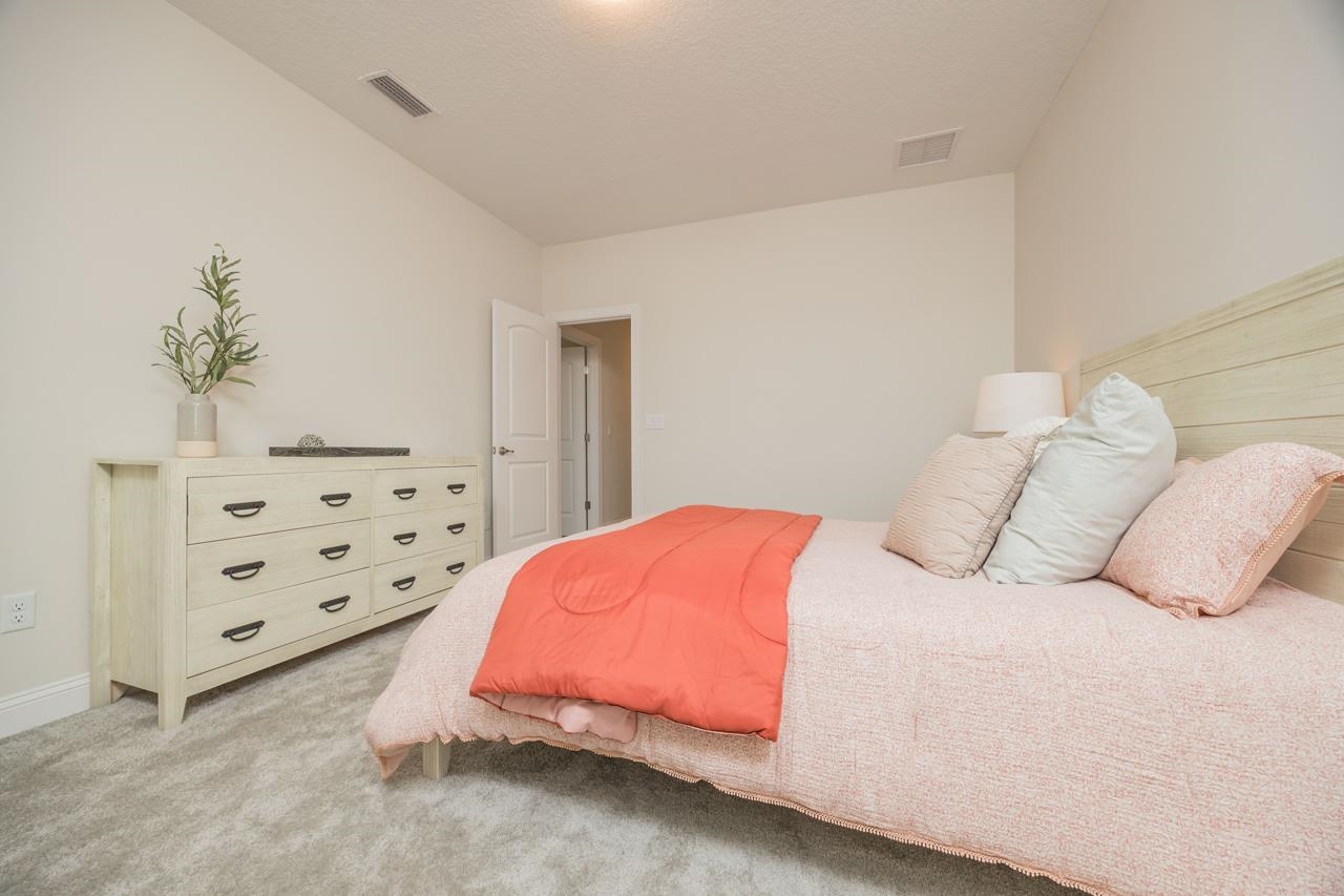 194 Snowbell Court St. Augustine, FL 32095 - Photo 26 of 75 a bedroom with a bed and dresser with potted plants