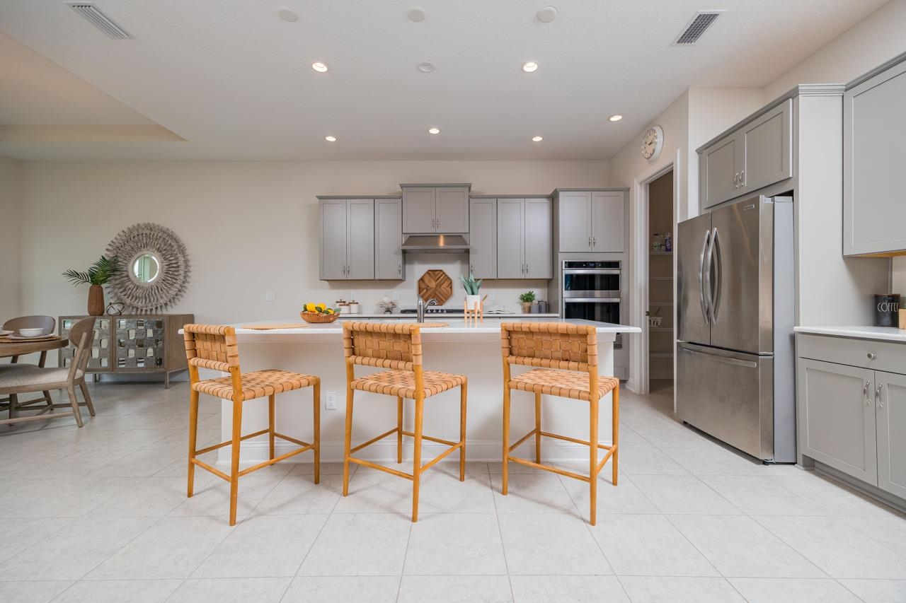 194 Snowbell Court St. Augustine, FL 32095 - Photo 53 of 75 a kitchen with stainless steel appliances kitchen island granite countertop a refrigerator and a stove top oven
