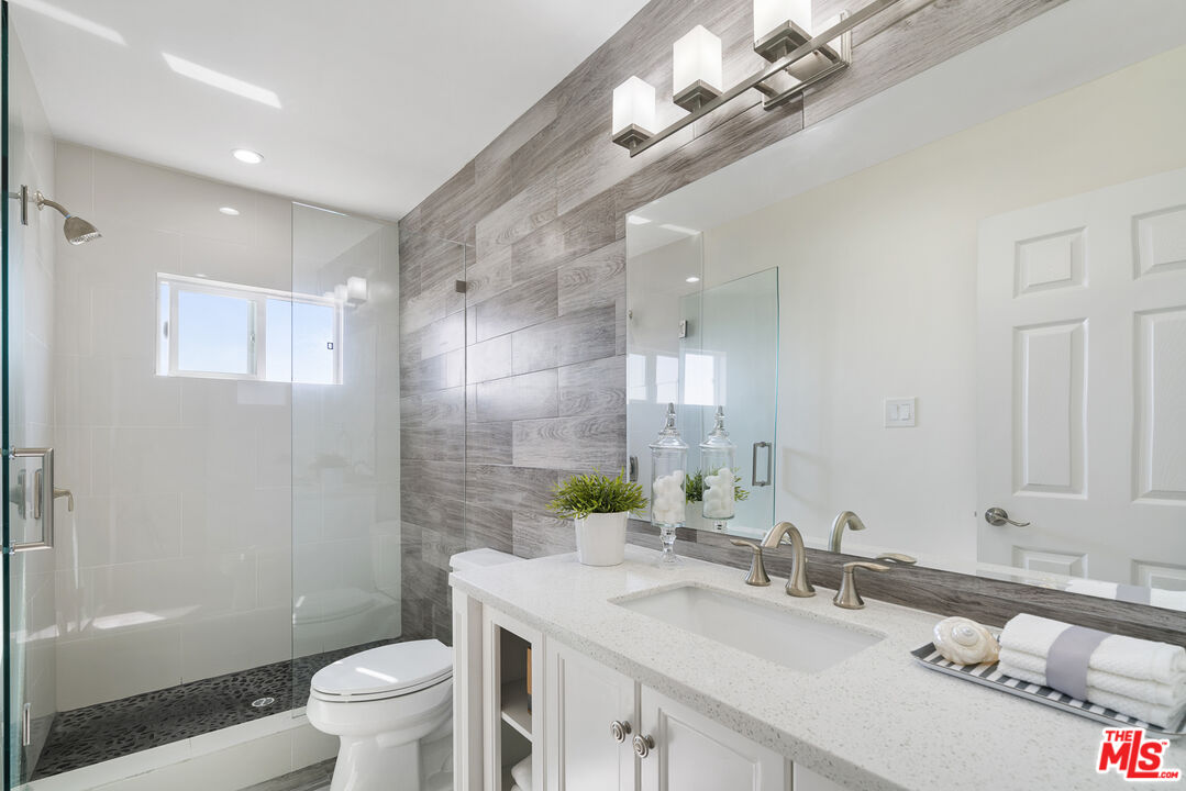 18147 Coastline Drive, Unit 6 Malibu, CA 90265 - Photo 13 of 26 a bathroom with a granite countertop sink a toilet a mirror and shower