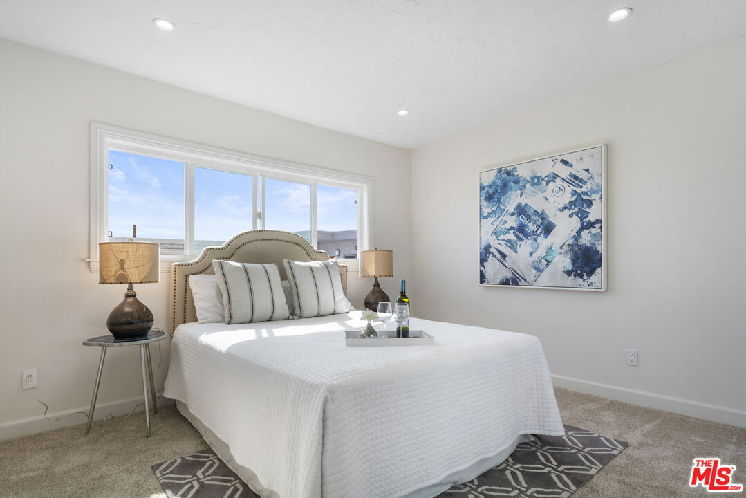 18147 Coastline Drive, Unit 6 Malibu, CA 90265 - Photo 15 of 26 a bedroom with a bed and a painting on the wall