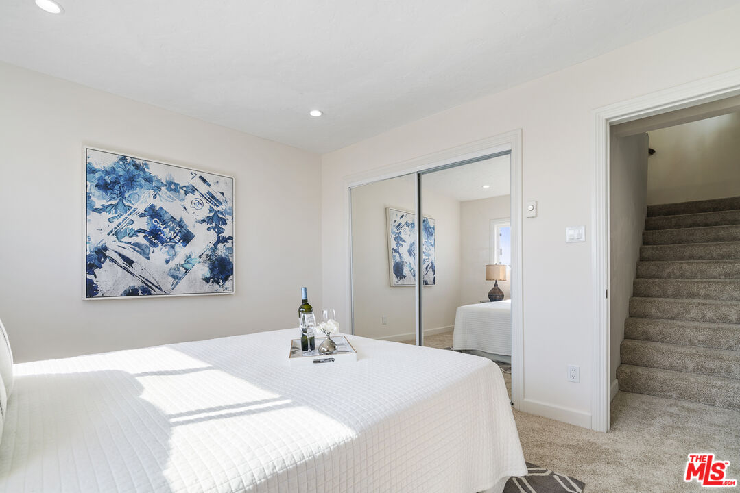 18147 Coastline Drive, Unit 6 Malibu, CA 90265 - Photo 16 of 26 a spacious bedroom with a bed and a painting on the wall