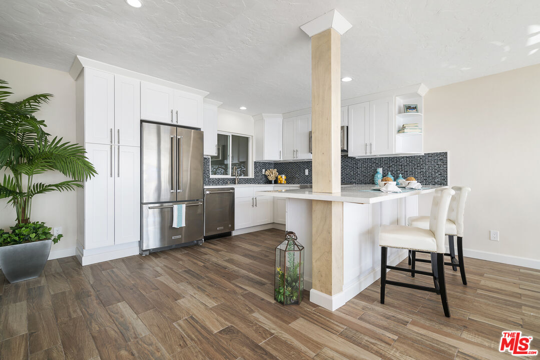 18147 Coastline Drive, Unit 6 Malibu, CA 90265 - Photo 6 of 26 a kitchen with white cabinets and stainless steel appliances
