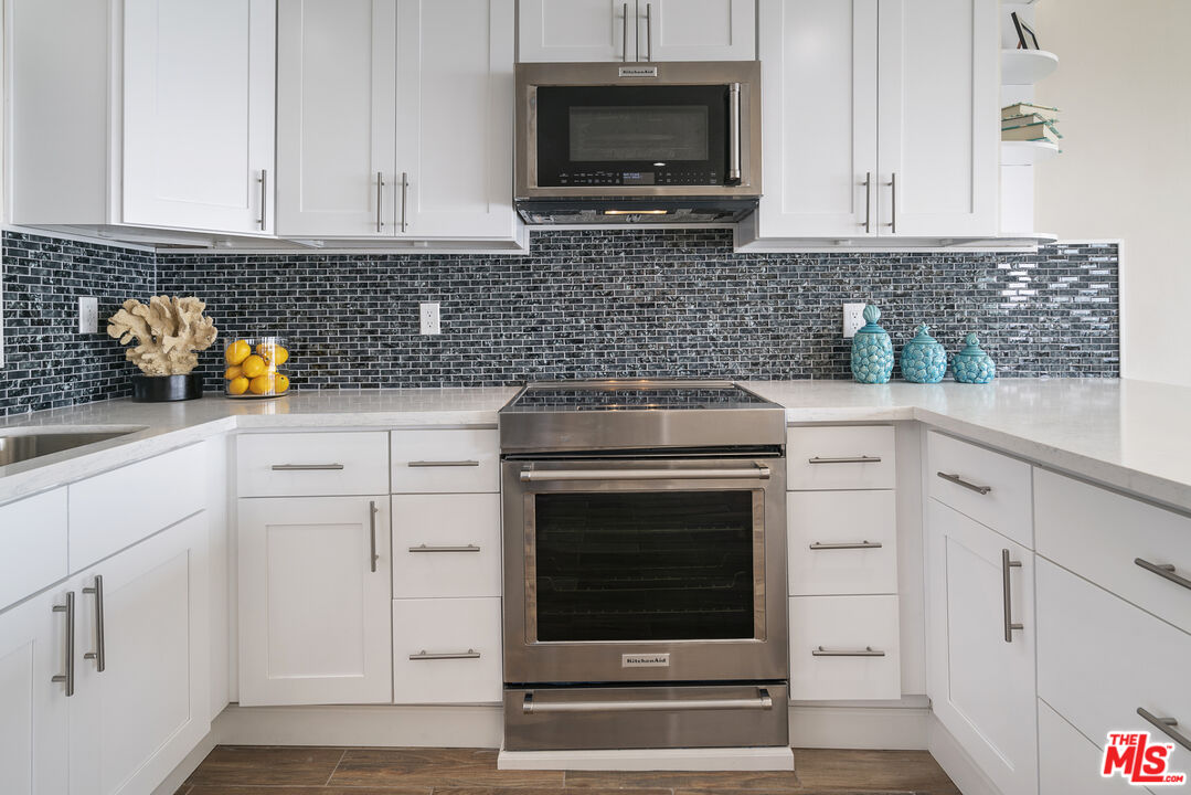 18147 Coastline Drive, Unit 6 Malibu, CA 90265 - Photo 8 of 26 a kitchen with white cabinets and stainless steel appliances