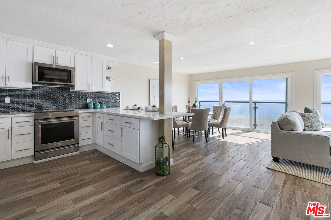 18147 Coastline Drive, Unit 6 Malibu, CA 90265 - Photo 9 of 26 a kitchen with stainless steel appliances a stove top oven a sink a dining table and chairs