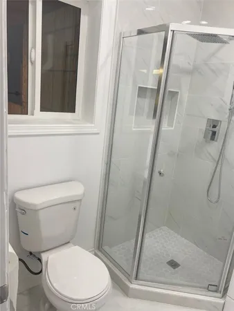 a white toilet next to a glass door shower