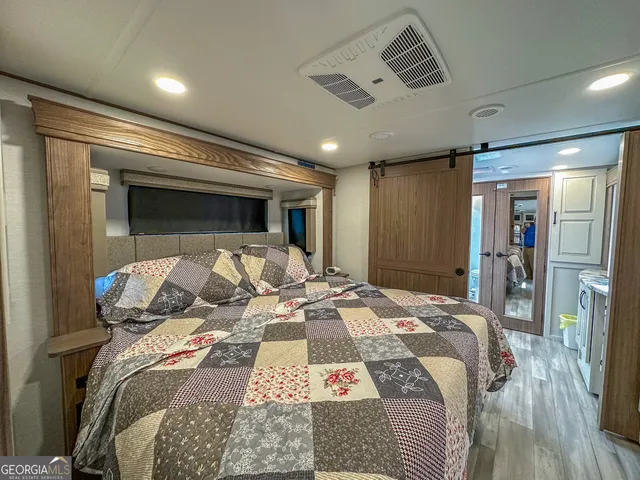 a bedroom with a bed and a flat tv screen on dresser