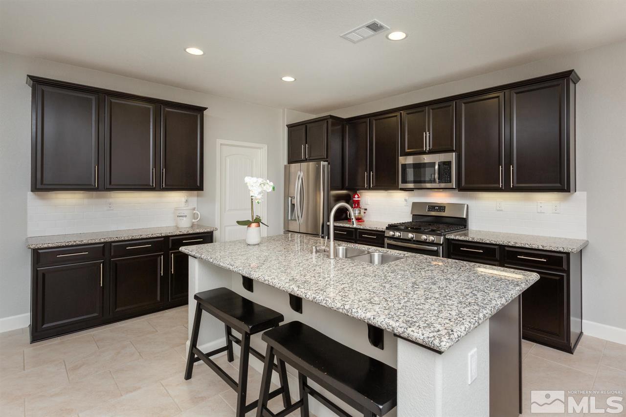 1830 Cascade Stable Lane Reno, NV 89521 - Photo 6 of 25 a kitchen with kitchen island granite countertop a stove microwave and refrigerator