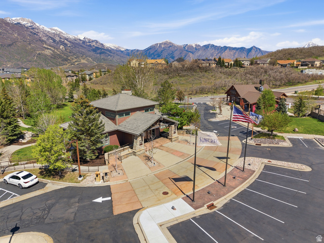2007 Fielding Hill Lane Draper, UT 84020 - Photo 59 of 83 Mountain backdrop featuring a multi-story building with a tile roof, an expansive parking area, paved walkways, and mature landscaping