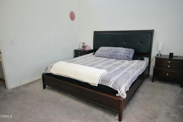 a bedroom with a bed and a lamp on dresser