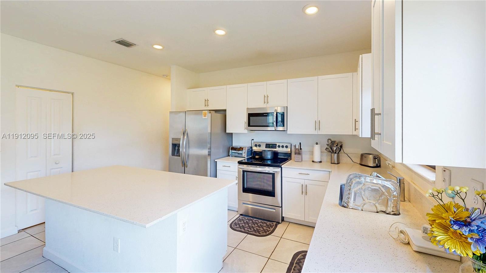 11964 Southwest 244th Street Homestead, FL 33032 - Photo 11 of 62 a kitchen with a sink a stove and white cabinets