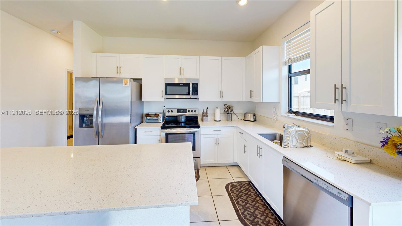 11964 Southwest 244th Street Homestead, FL 33032 - Photo 12 of 62 a kitchen with a sink a refrigerator a window and cabinets