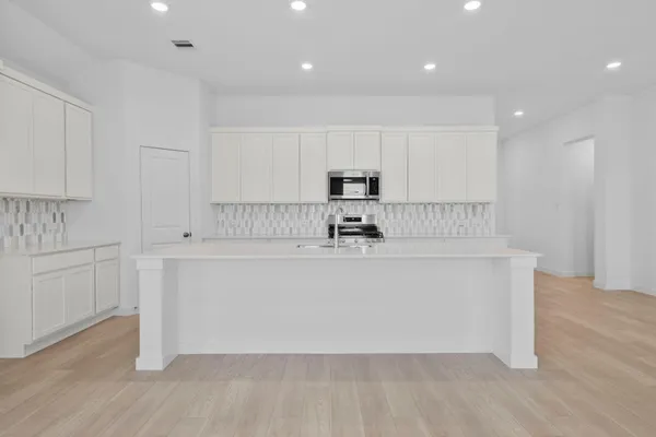 a room with kitchen island white cabinets and stainless steel appliances