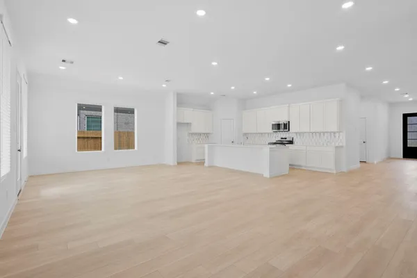 a view of an empty room with kitchen island white cabinetry and refrigerator