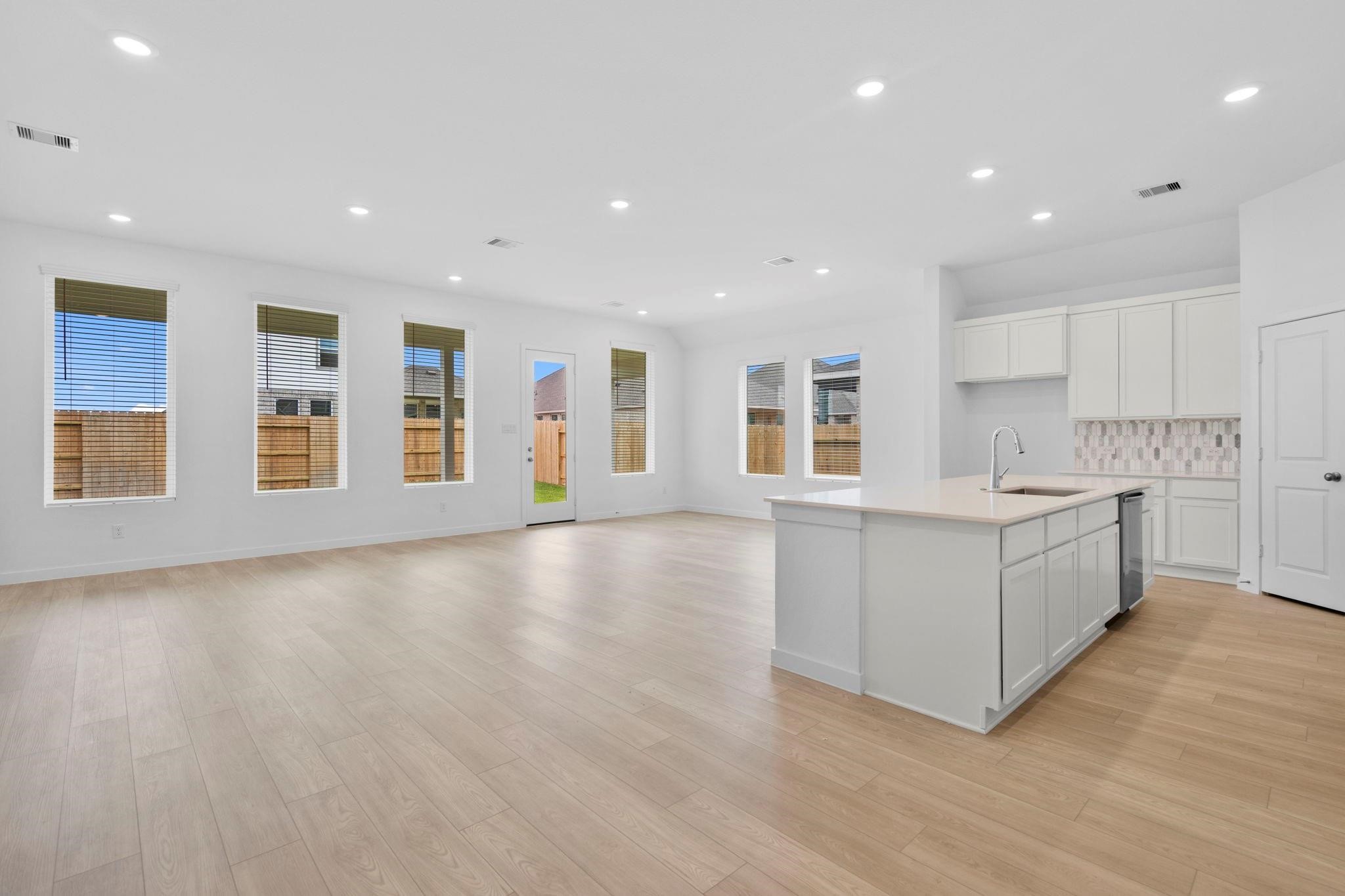 2716 Pine Bluff Drive Rosenberg, TX 77469 - Photo 7 of 32 a large white kitchen with kitchen island a sink wooden floor and a refrigerator