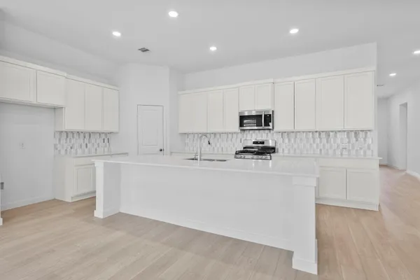 a kitchen with granite countertop white cabinets and stainless steel appliances