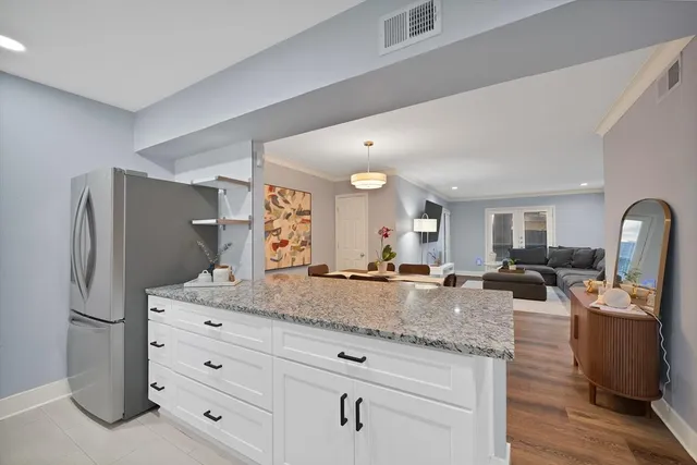 a view of living room with granite countertop stainless steel appliances white cabinets and wooden floor