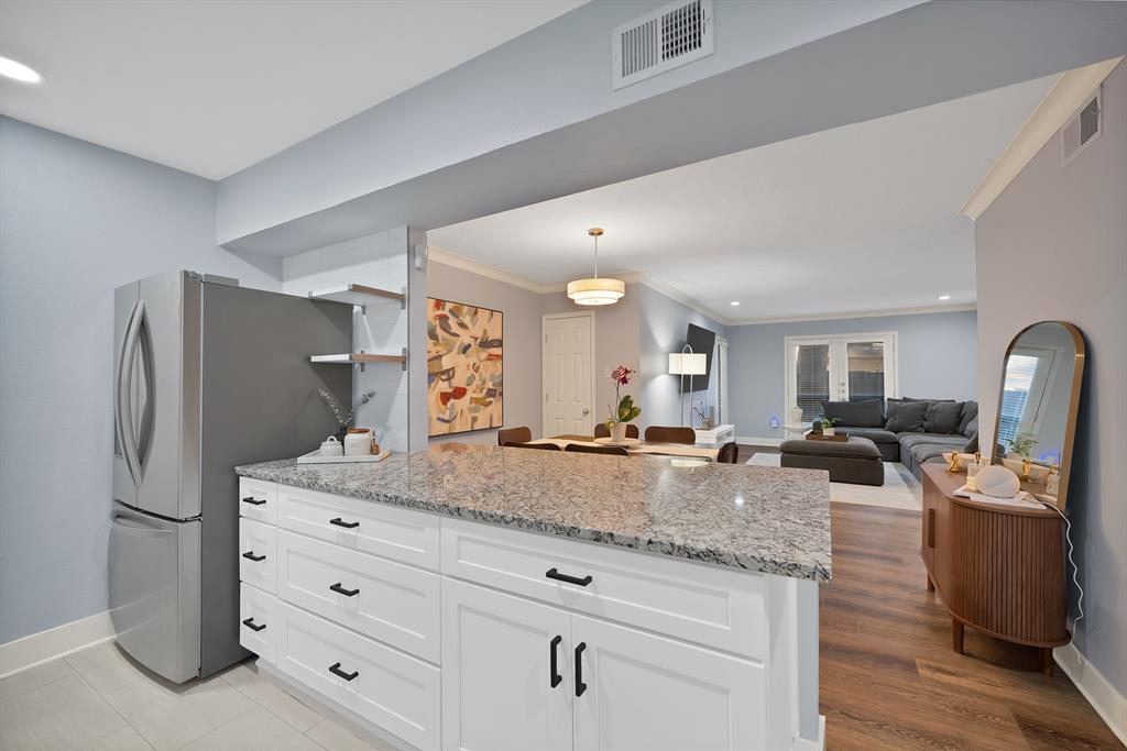 a view of living room with granite countertop stainless steel appliances white cabinets and wooden floor