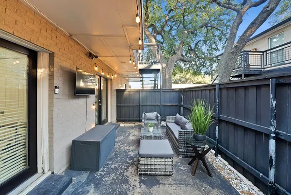 a view of a patio with couches chairs potted plants and wooden fence