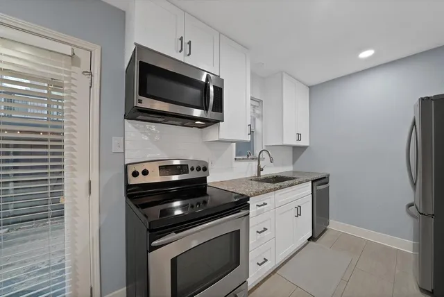 a kitchen with stainless steel appliances a stove microwave and sink