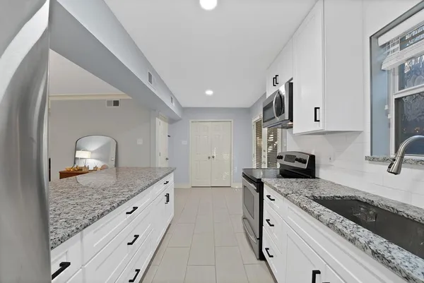 a kitchen with granite countertop stainless steel appliances sink stove and cabinets