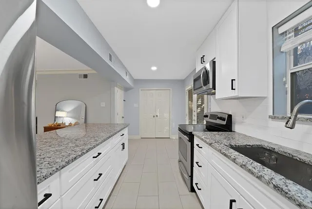 a kitchen with granite countertop stainless steel appliances sink stove and cabinets