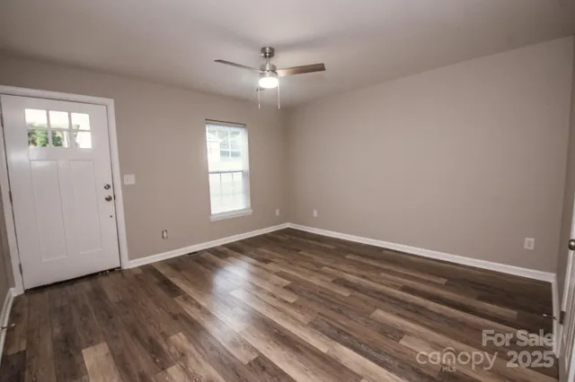 a view of an empty room with wooden floor and a window