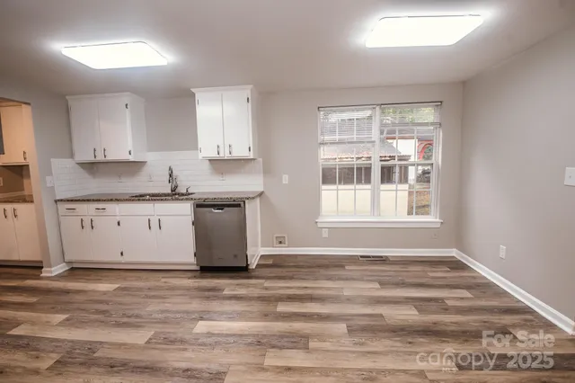 a view of kitchen with granite countertop window sink and cabinets