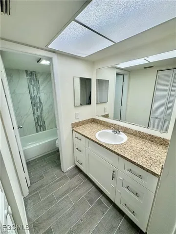 a bathroom with a granite countertop sink a mirror and a bathtub