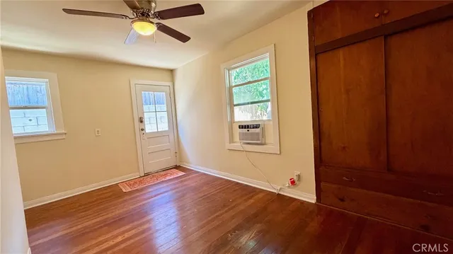 a view of an empty room with a window and wooden floor