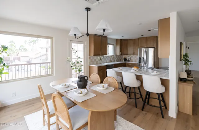 a view of a dining room and livingroom with furniture wooden floor a rug a fireplace and a chandelier