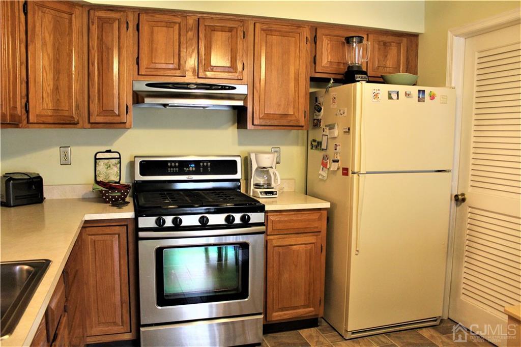 5103 Stonehedge Road, Unit 5103 Edison, NJ 08820 - Photo 7 of 25 a kitchen with stainless steel appliances wooden cabinet and a refrigerator