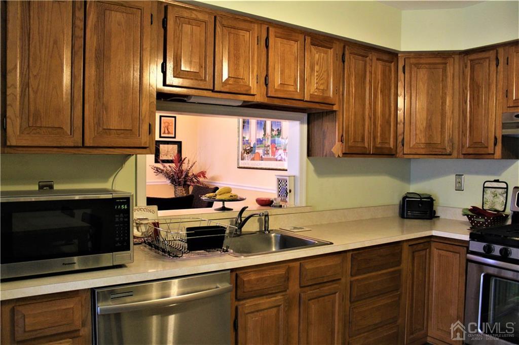 5103 Stonehedge Road, Unit 5103 Edison, NJ 08820 - Photo 8 of 25 a kitchen with stainless steel appliances wooden cabinets and a stove top oven