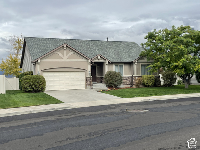 1706 Renaissance Way Springville, UT 84663 - Photo 1 of 31 Stucco exterior with stone accents, attached two-car garage, concrete driveway, lush lawn, and mature landscaping