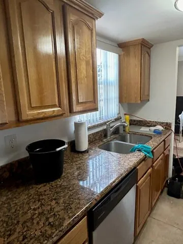 a kitchen with granite countertop a sink a stove and wooden cabinets